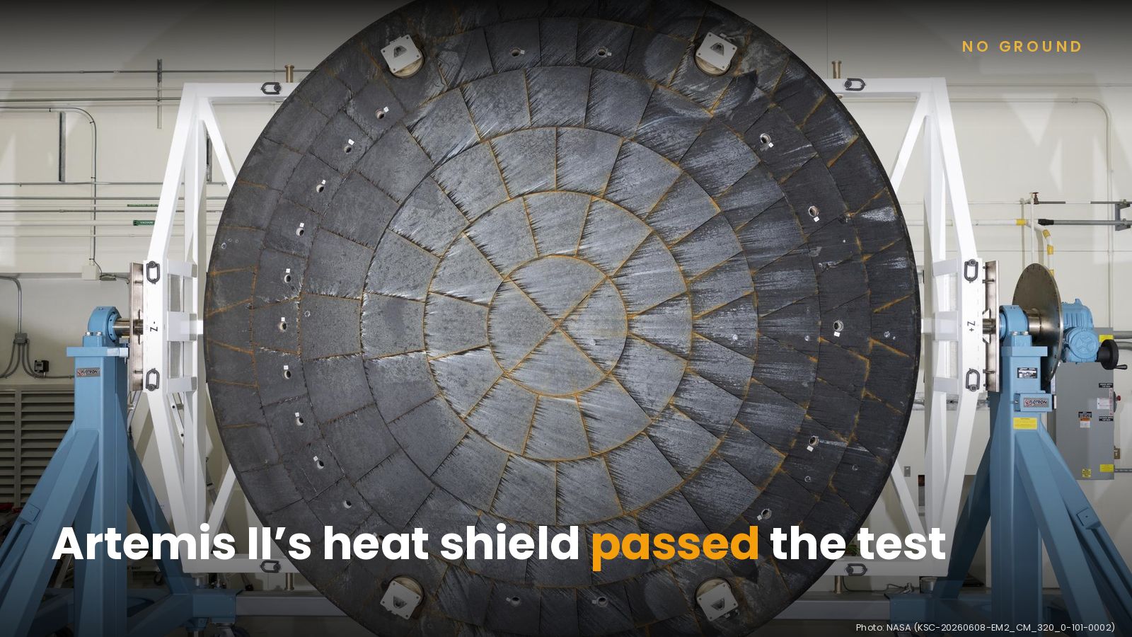 The round, dark Artemis II Orion heat shield, made of Avcoat blocks with orange-tinted seams, standing upright on blue stands, with the headline Artemis II’s heat shield passed the test