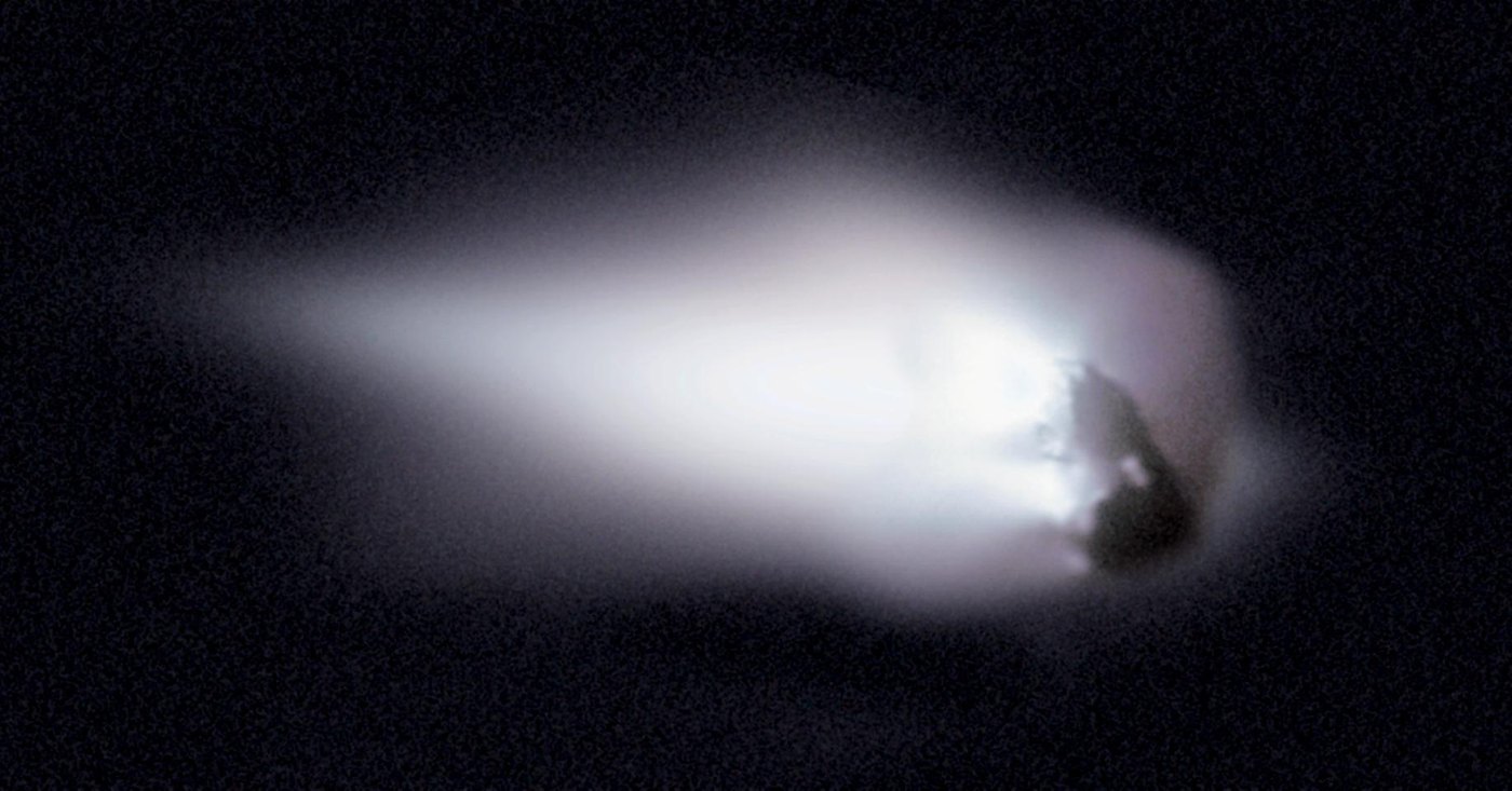 Grainy image of the dark, elongated nucleus of Halley's Comet, with bright jets of dust