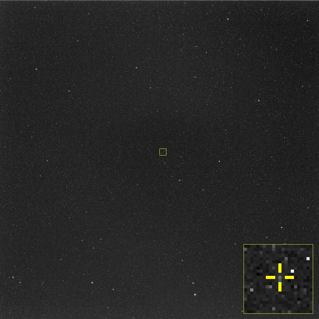 A dark star field with a small yellow box marking a faint point of light, and an enlarged inset in the corner with yellow crosshairs on it