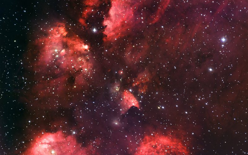 Optical telescope image of the Cat’s Paw Nebula, NGC 6334: red glowing hydrogen clouds shaped like a paw print against a star field