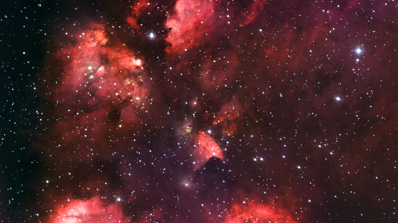 Optical telescope image of the Cat’s Paw Nebula, NGC 6334: red glowing hydrogen clouds shaped like a paw print against a star field