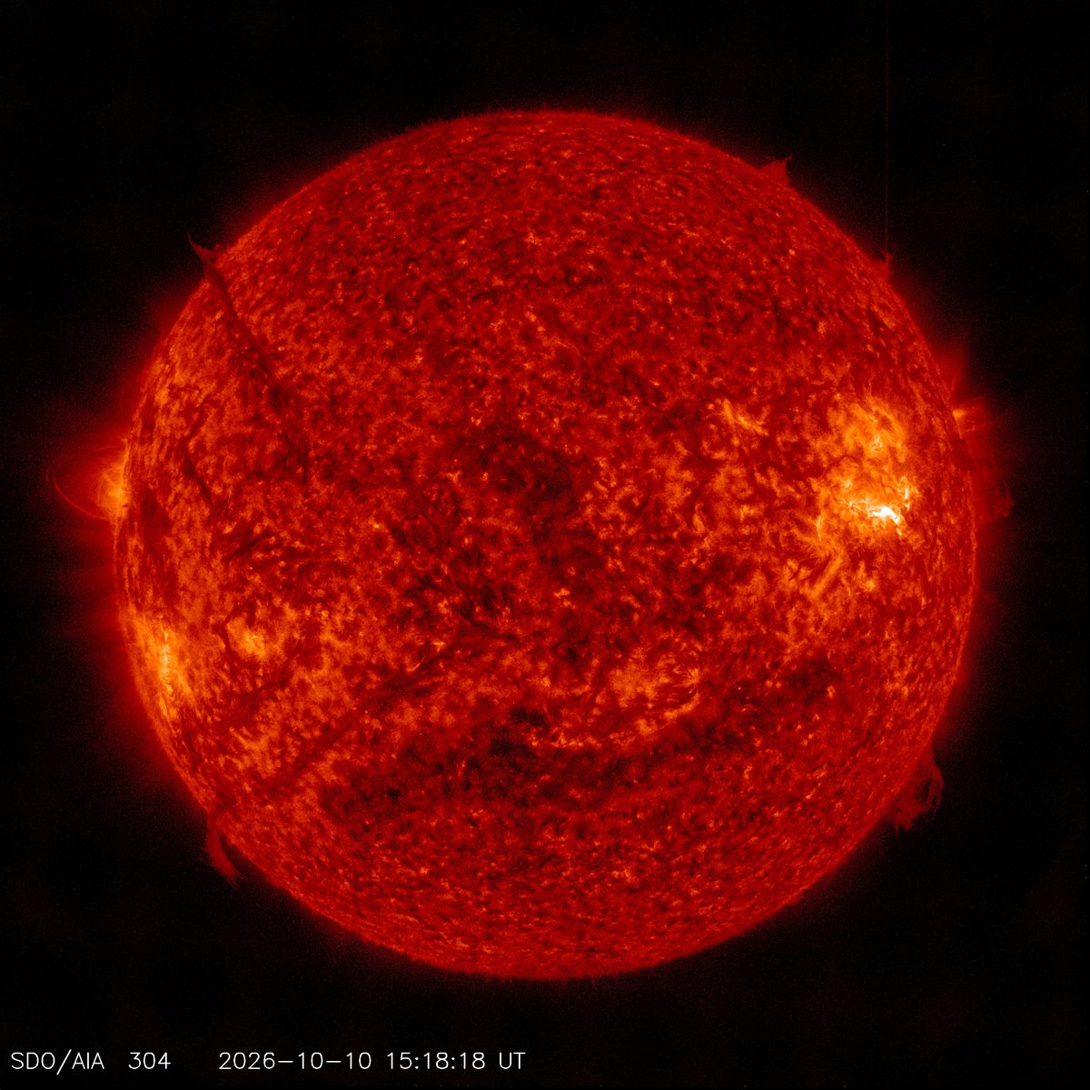 Full disk of the Sun in red-orange extreme-ultraviolet light with a bright white flare on the right side of the disk, Oct. 10, 2026, 15:18:18 UTC