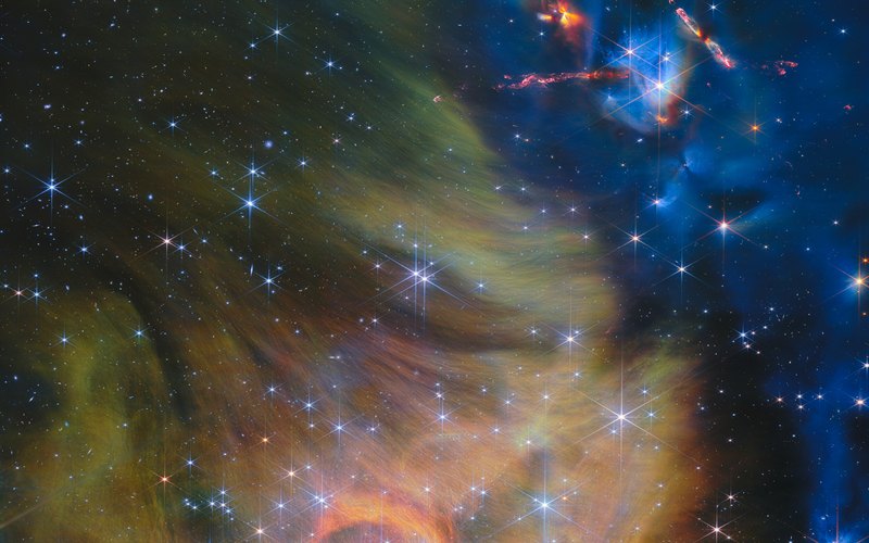 Near-infrared Webb view of IC 348: gold and green dust clouds, blue sky, and red jets from protostars at upper right
