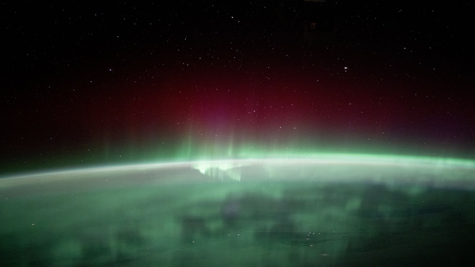 Green and red aurora borealis glowing over Earth’s limb, photographed from the International Space Station above Manitoba, Canada — NASA iss072e159172