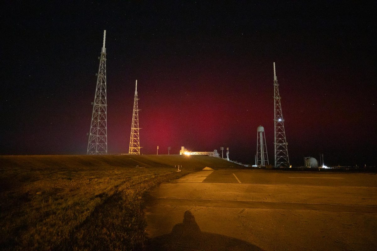 Faint red aurora glow low in the night sky behind the lightning towers of Launch Complex 39B at NASA’s Kennedy Space Center in Florida, Nov. 11, 2025