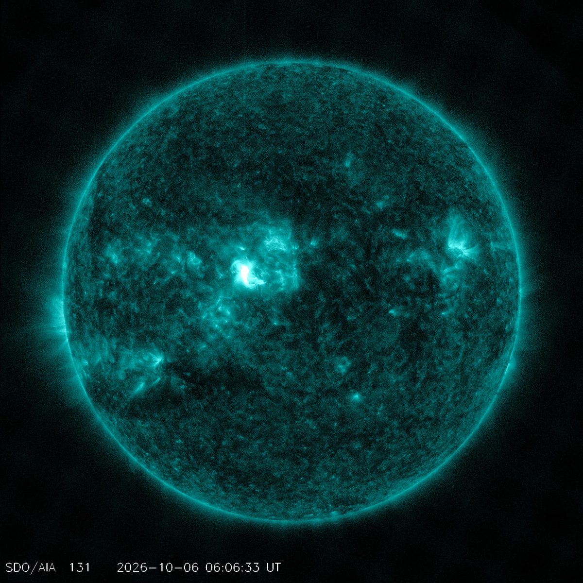 Full disk of the Sun in teal extreme-ultraviolet light from NASA’s Solar Dynamics Observatory, with a bright flare just above and left of center, Oct. 6, 2026, 06:06 UTC