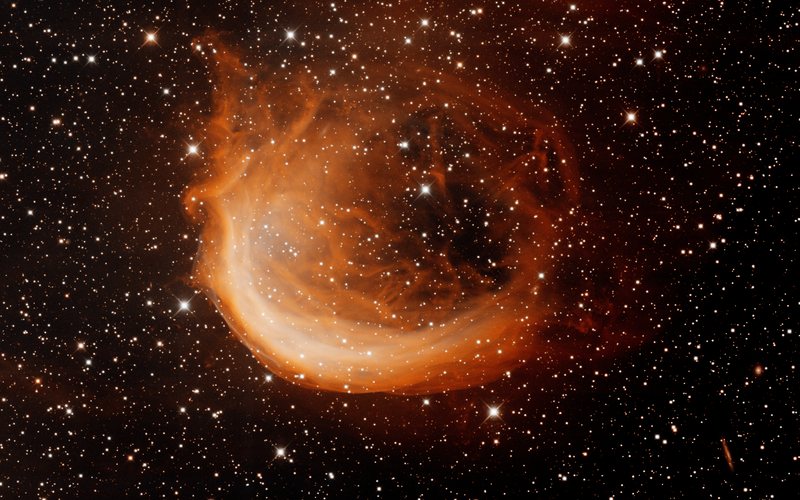 Crescent of glowing red and cyan gas — the Shrimp Nebula (Sh2-188) in Cassiopeia