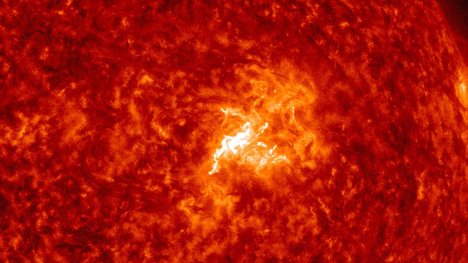 Close-up of the Sun in red extreme-ultraviolet light from NASA’s Solar Dynamics Observatory, with a bright white M6.7 flare erupting from sunspot Region 4549, Oct. 8, 2026