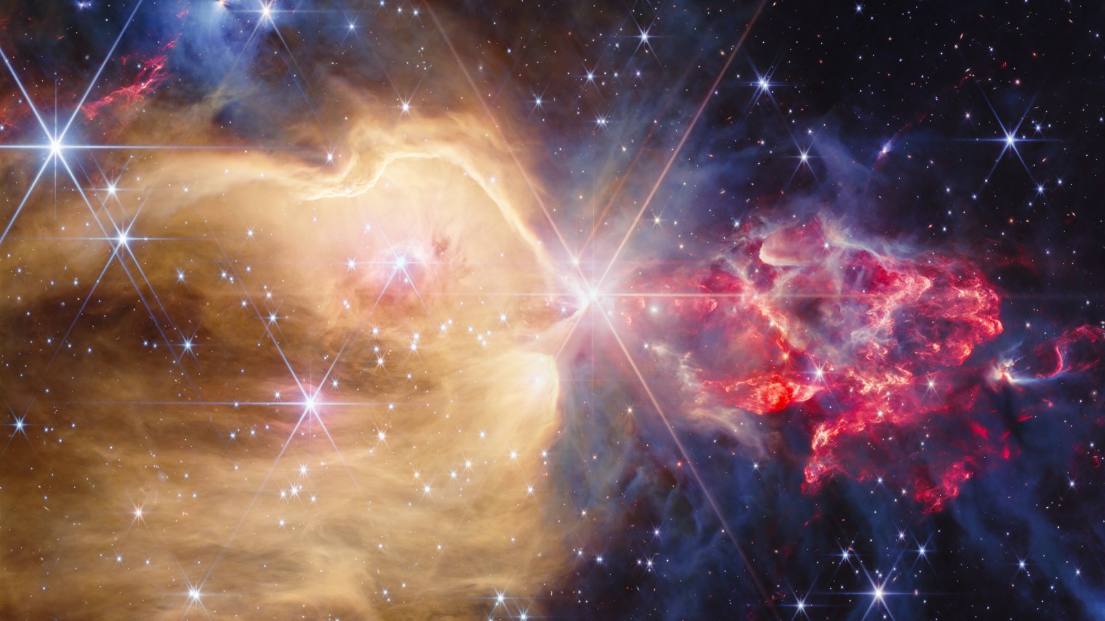 James Webb NIRCam image of NGC 7129: golden glowing cavity left of a bright central star, clumpy red shocked gas and protostar outflows on the right, gray dense dust, many stars with eight-point diffraction spikes